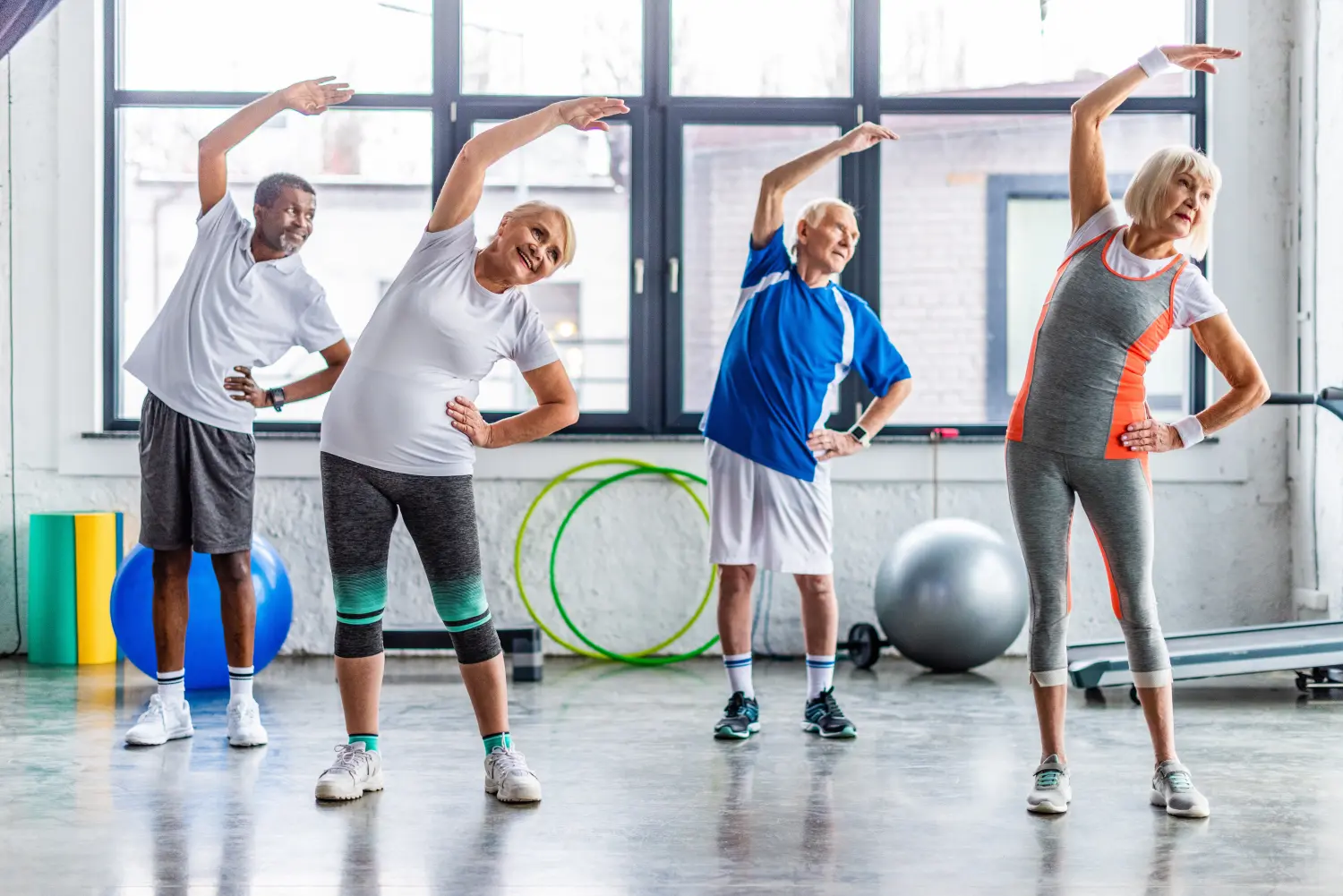 Glückliche multiethnische ältere Sportler, die in der Sporthalle synchron trainieren